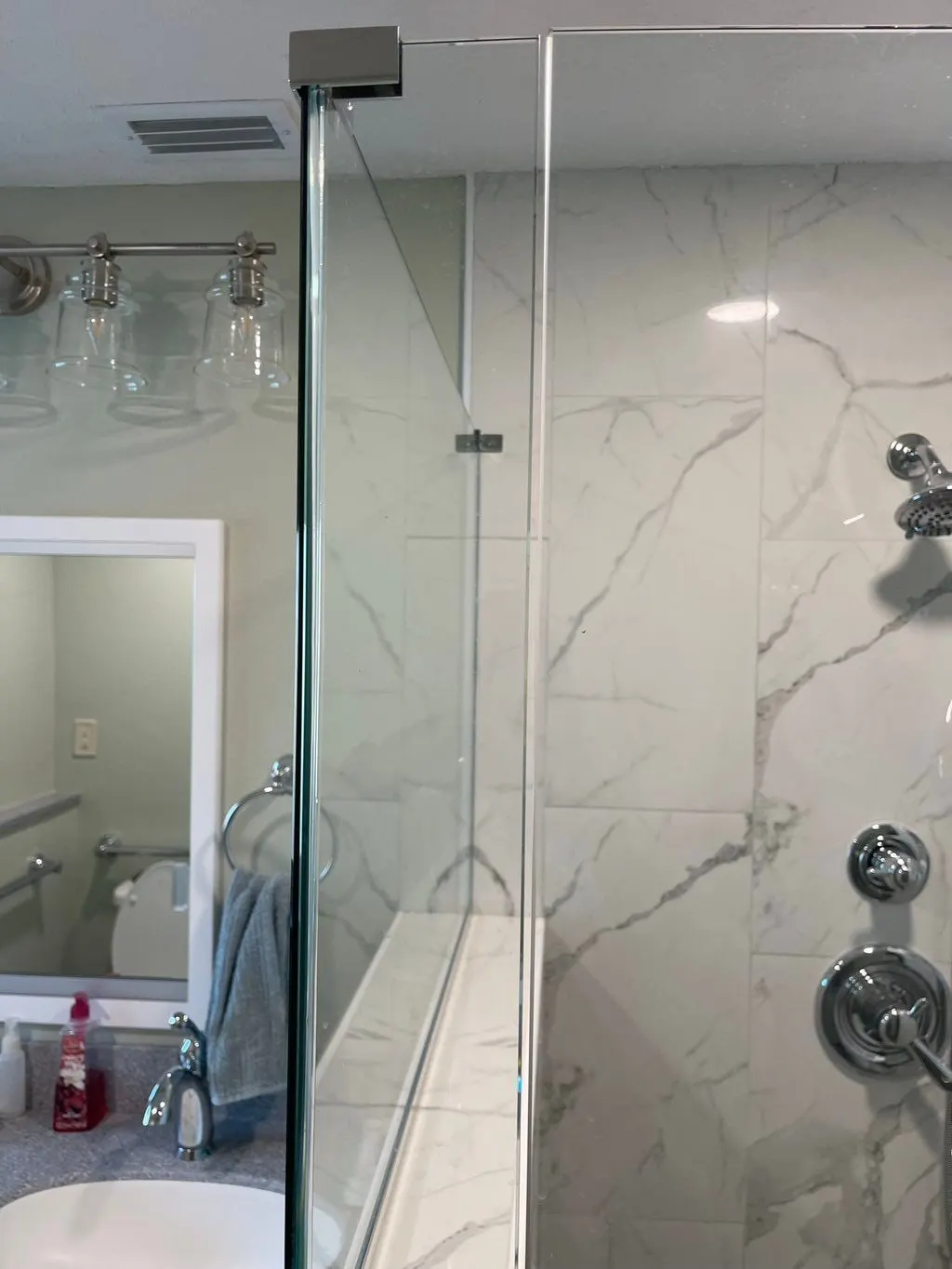 Walk-in shower with marble-look tile and a frameless glass enclosure