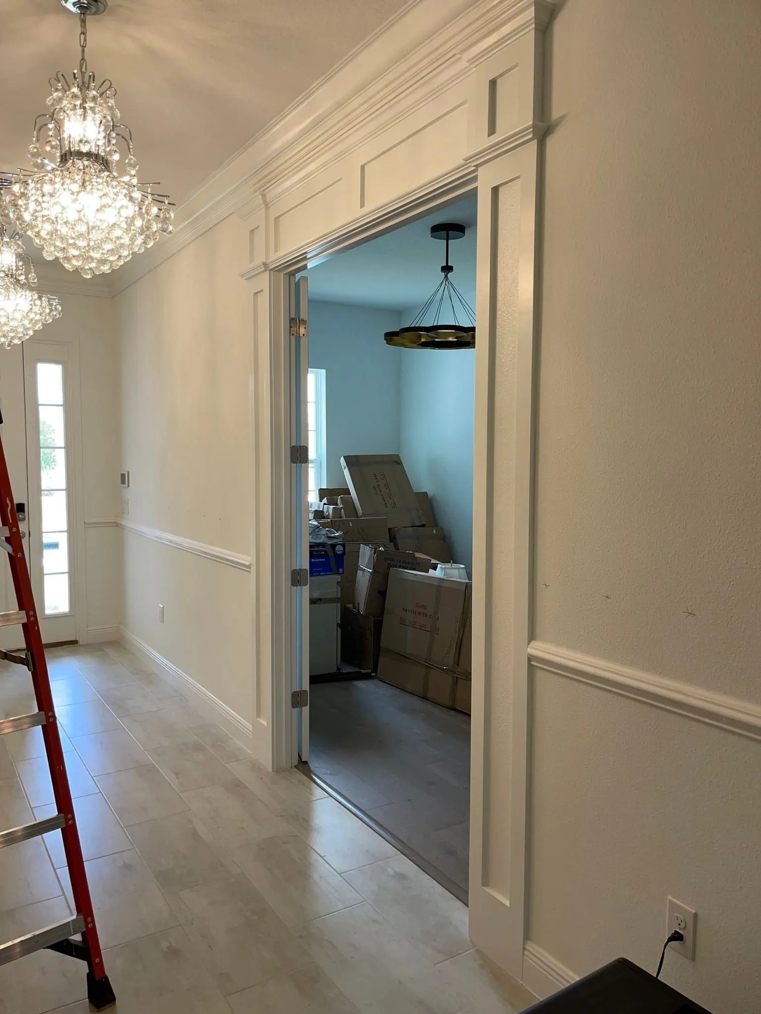 Entry with built-up door casing, chair rail and a crystal chandelier