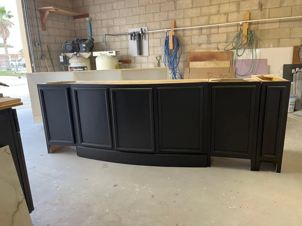 Black island base with a curved front, before its countertop goes on