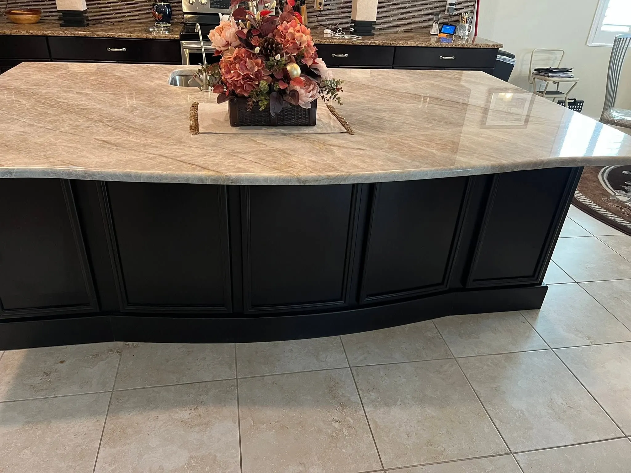 Black painted island with raised-panel ends and a curved stone countertop