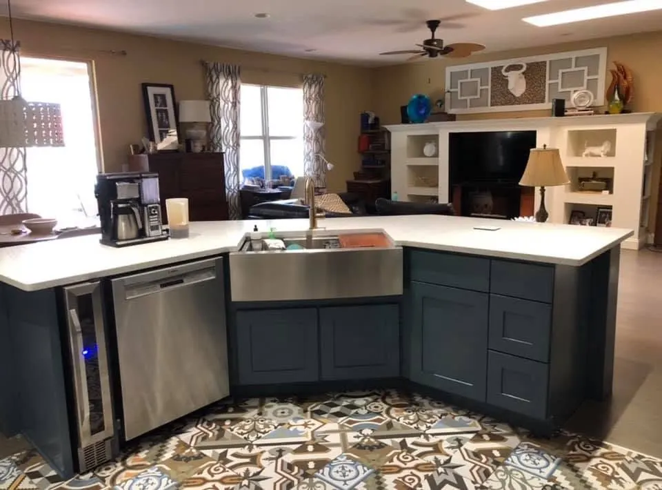 Navy lower cabinets with a farmhouse sink and wine fridge under white uppers