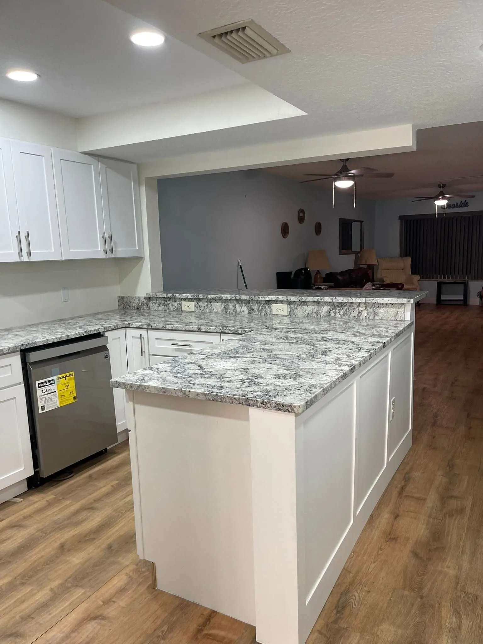 White island with paneled sides and a granite top in an open kitchen