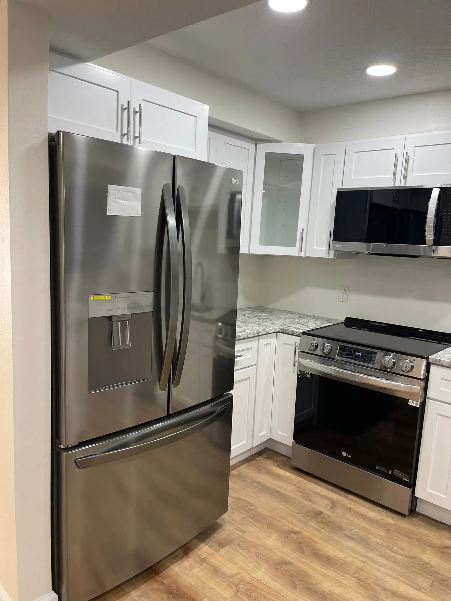 White cabinets fitted around a stainless French-door refrigerator and range
