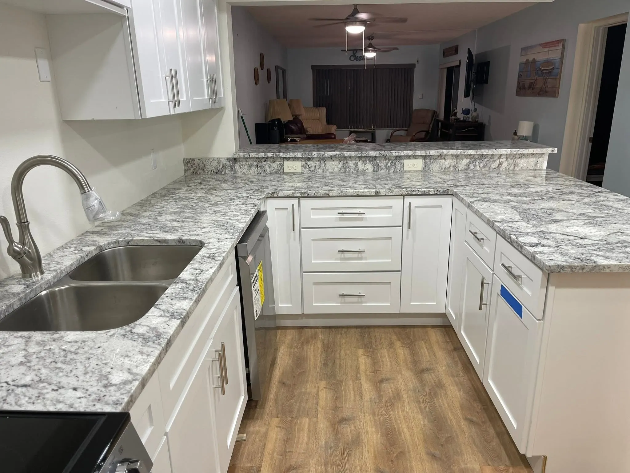 U-shaped white kitchen with gray-veined granite counters, open to the living room