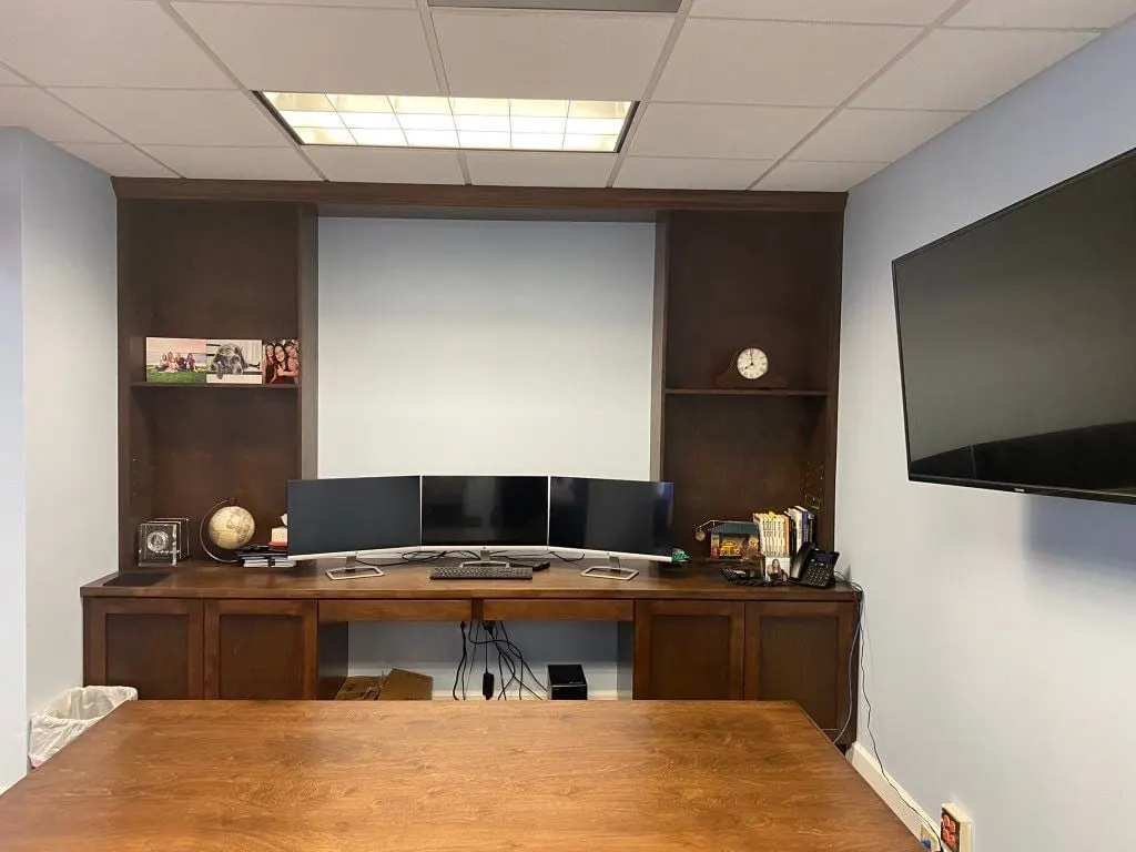 Office with a dark wood built-in wall of shelves and cabinets behind a desk