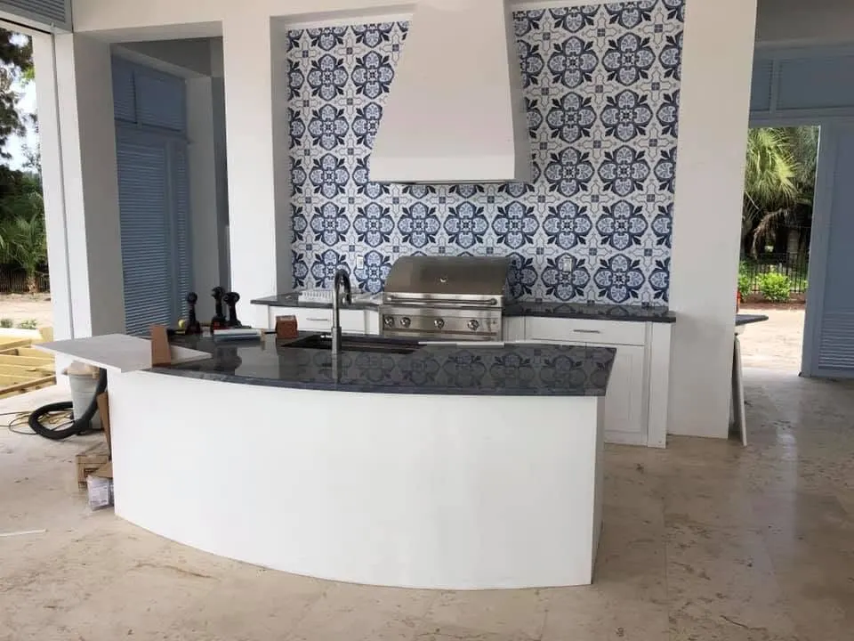 Outdoor kitchen with a curved white counter, built-in grill and blue patterned tile