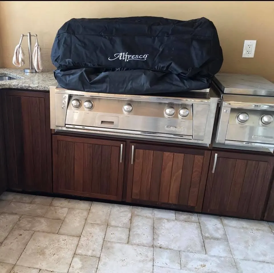 Covered built-in grill over wood-look outdoor cabinets with a stone top