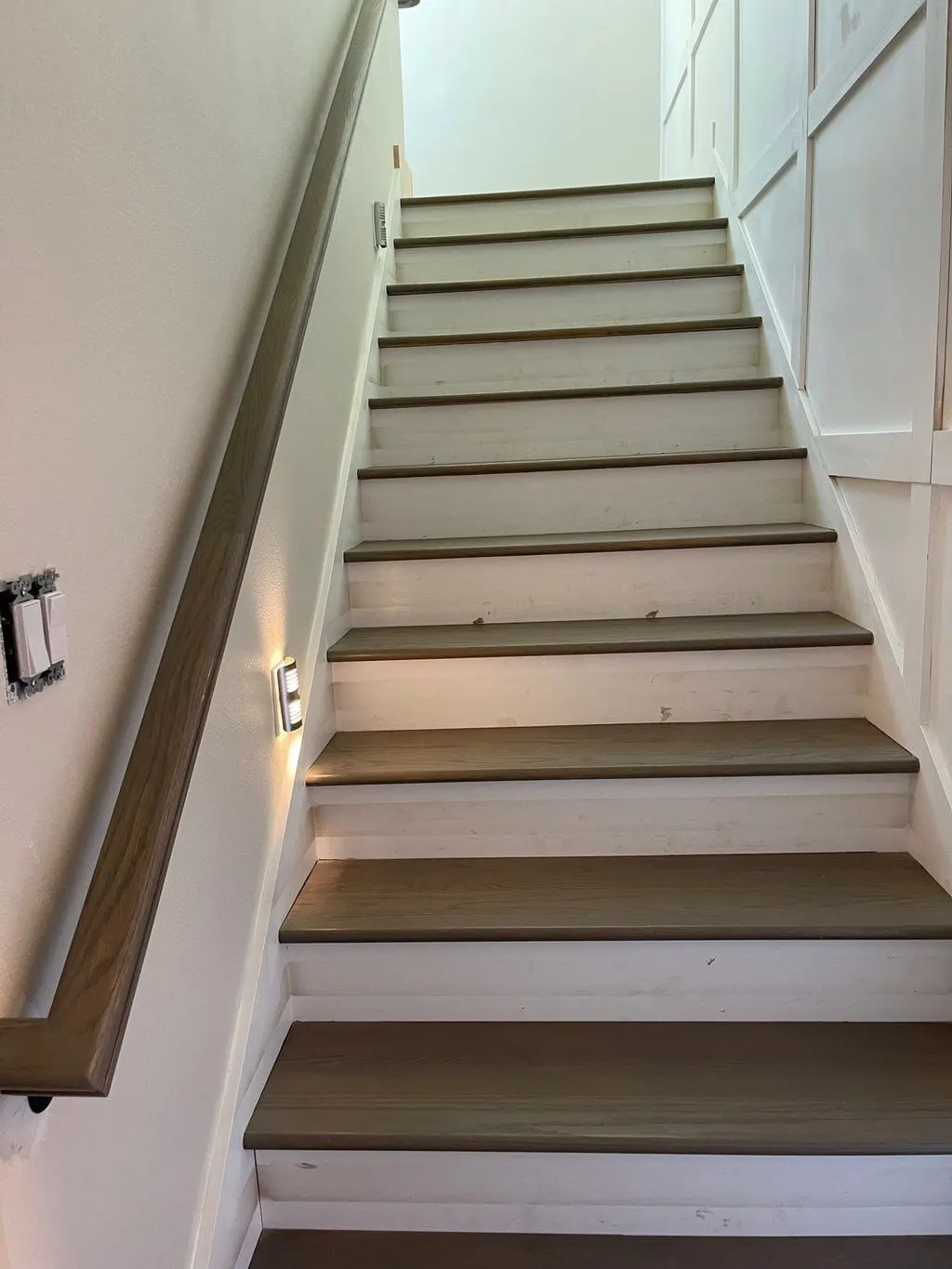 Stairway with paneled walls, white risers and dark treads
