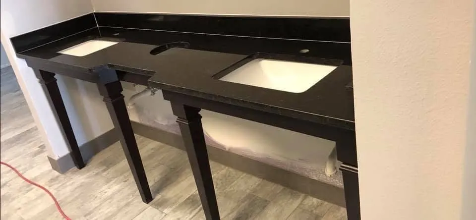 Dark double console vanity with a black stone top and two undermount sinks